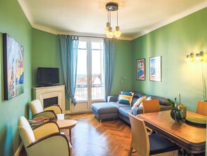 A living room with a fireplace, a sofa, a dining table, and a television. - Spacious 3-bedroom apartment in delightful Cannes with AC - LES BANANIERS (Cannes)