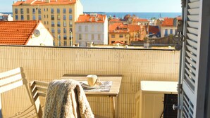 A balcony with a table, a chair, and a blanket. - Spacious 3-bedroom apartment in delightful Cannes with AC - LES BANANIERS (Cannes)