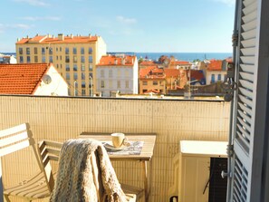 En balkon med et bord, en stol og et tæppe.