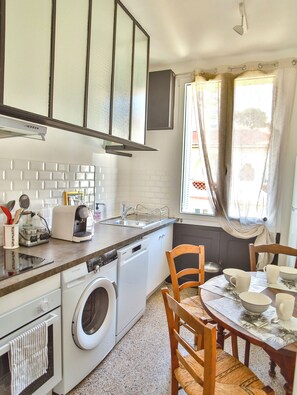 Una cocina equipada con lavadora, lavavajillas, fregadero y comedor con sillas y mesa.