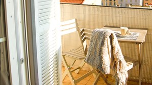 A balcony with a table, chairs, and a view of buildings and the sea. - Spacious 3-bedroom apartment in delightful Cannes with AC - LES BANANIERS (Cannes)
