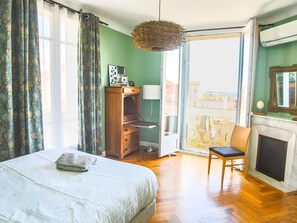 A bedroom with a bed, a dresser, a chair, a fireplace, and a view through a glass door. - Spacious 3-bedroom apartment in delightful Cannes with AC - LES BANANIERS (Cannes)