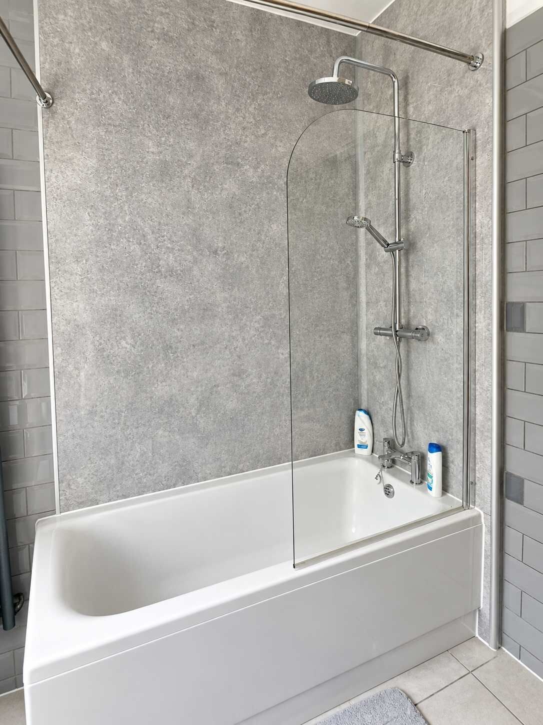 Une salle de bain moderne avec une douche à l’italienne, une baignoire blanche et un sol carrelé.