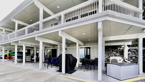 A covered outdoor patio with multiple seating areas, a grill, and a water heater. - The Lakeplace on Flathead close to GNP (Polson)