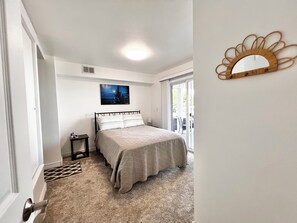 Een slaapkamer met een bed, een nachtkastje, een foto aan de muur en een raam.