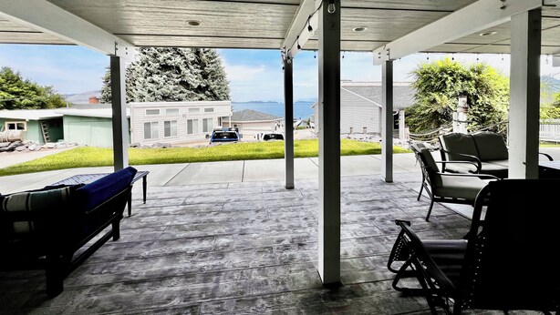 A covered outdoor area with a bench, chairs, and a bicycle. - The Lakeplace on Flathead close to GNP (Polson)