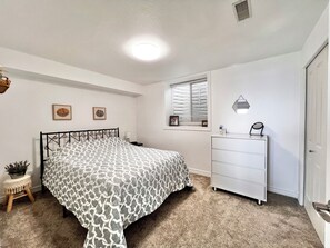 A bedroom with a bed, a dresser, a window with blinds, and a ceiling light. - The Lakeplace on Flathead close to GNP (Polson)