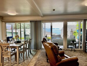 A spacious living room with a large sliding glass door leading to a balcony with a view of the sea. - The Lakeplace on Flathead close to GNP (Polson)