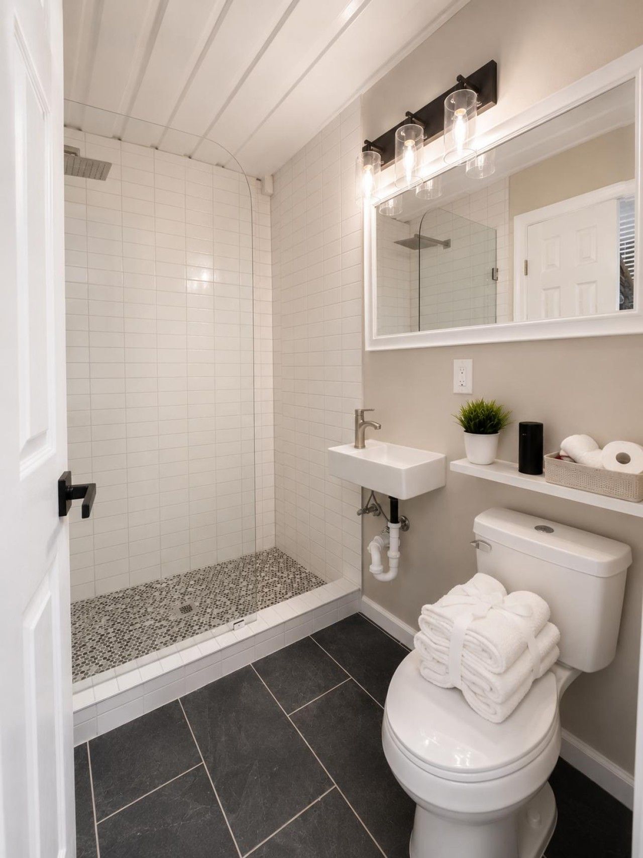 Un baño con ducha, inodoro, lavabo y un espejo con iluminación.