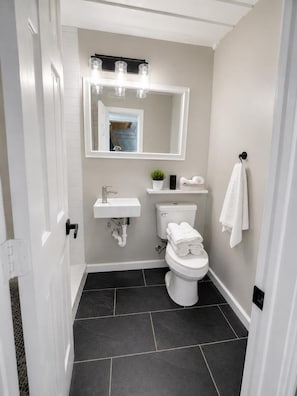 Un baño pequeño con un lavamanos blanco, un inodoro y un espejo con iluminación.