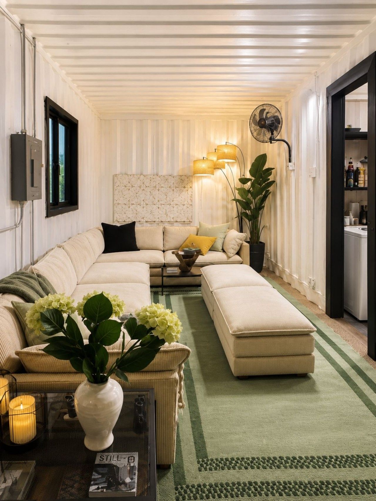 Een moderne woonkamer met een hoekbank, een salontafel met een bloevas, een vloerlamp en een groot raam.