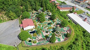 An aerial view of a golf course with a clubhouse, parking area, and surrounding greenery. - Helen Cabin w/ Deck & Hot Tub 1/3 Mi to Main St (Helen)