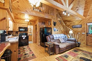 A cabin interior with a kitchen, a dining area, a living room with a sofa, and a staircase. - Helen Cabin w/ Deck & Hot Tub 1/3 Mi to Main St (Helen)