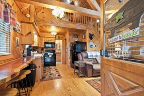 A cabin interior with a kitchen, dining area, and a living room with a sofa. - Helen Cabin w/ Deck & Hot Tub 1/3 Mi to Main St (Helen)