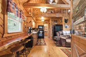 Ein Interieur einer Hütte mit Küche, Essbereich und einer gemütlichen Sitzecke.