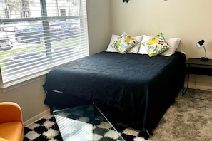 A bedroom with a bed, a window with blinds, a nightstand, and a chair. - Modern Comfort Getaway- 2bd 1bath Free Parking (Woodland)