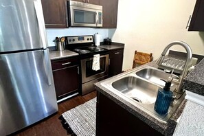 A kitchen with stainless steel appliances, a microwave, a stove, and a sink with a soap dispenser. - Modern Comfort Getaway- 2bd 1bath Free Parking (Woodland)