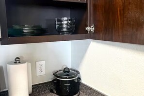 A kitchen with a black slow cooker on the counter, a roll of paper towels, and a glass bowl on the shelf above. - Modern Comfort Getaway- 2bd 1bath Free Parking (Woodland)