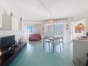 A modern living room with a flat-screen TV, a dining area with a glass table, and a sofa. - Casa Port Latin: Terrace, Wi-Fi, beaches within walking distance (Fréjus)