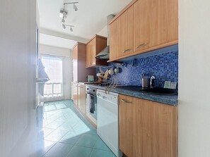A kitchen with wooden cabinets, a tiled backsplash, and a dishwasher. - Casa Port Latin: Terrace, Wi-Fi, beaches within walking distance (Fréjus)