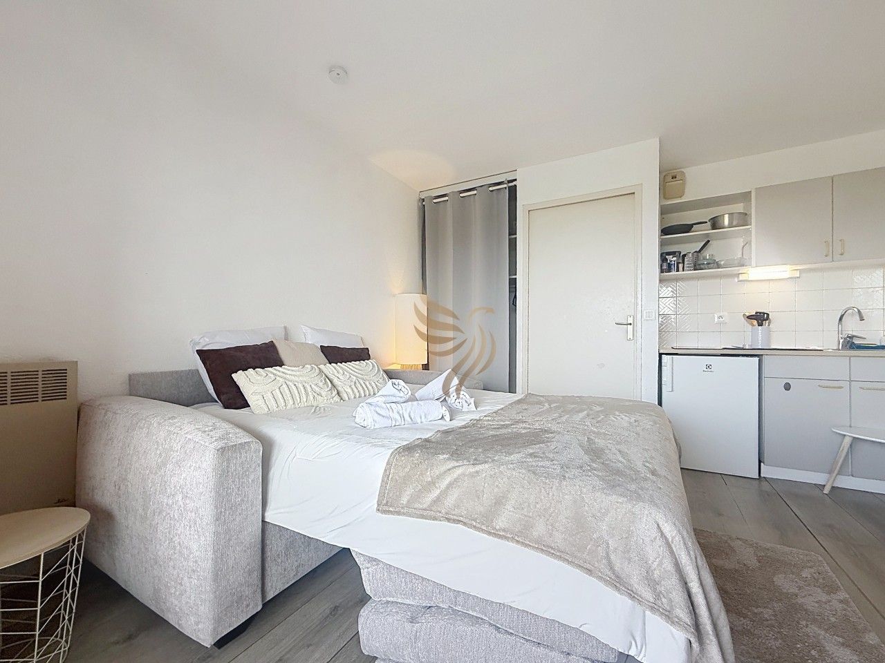 Een moderne hotelkamer met een bed, nachtkastje en een kitchenette.