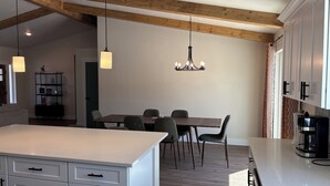 A modern kitchen with white cabinetry, a central island, and a dining area with chairs.