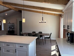A modern kitchen with white cabinetry, a central island, and a dining area with chairs.