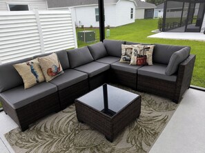 Ein Ecksofa mit einem Glastisch in einer Gartenanlage.