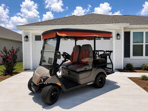 Ein Golfmobil steht vor einem Haus mit Garage.