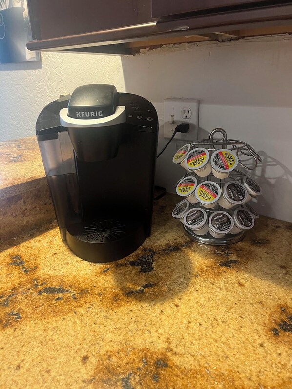 En Keurig-kaffemaskin står på en bänkskiva bredvid ett ställ för kaffekapslar, och i stället finns det flera kapslar.