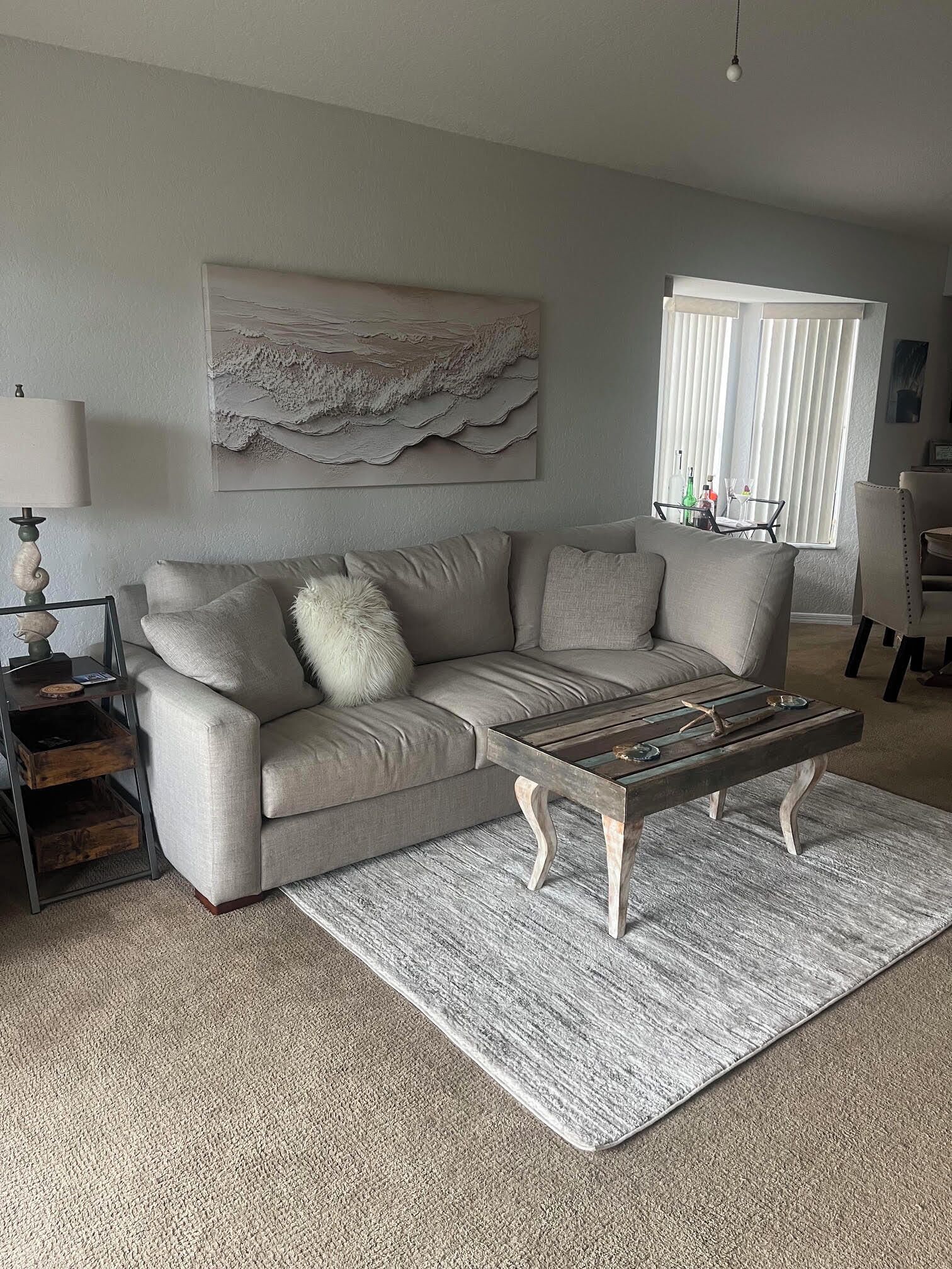 A living room with a sofa, a coffee table, a lamp, and a painting on the wall.