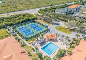 A residential property with a tennis court, swimming pool, and a covered patio area. - NSB Coastal Escape - 3BR Riverside Condo (New Smyrna Beach)