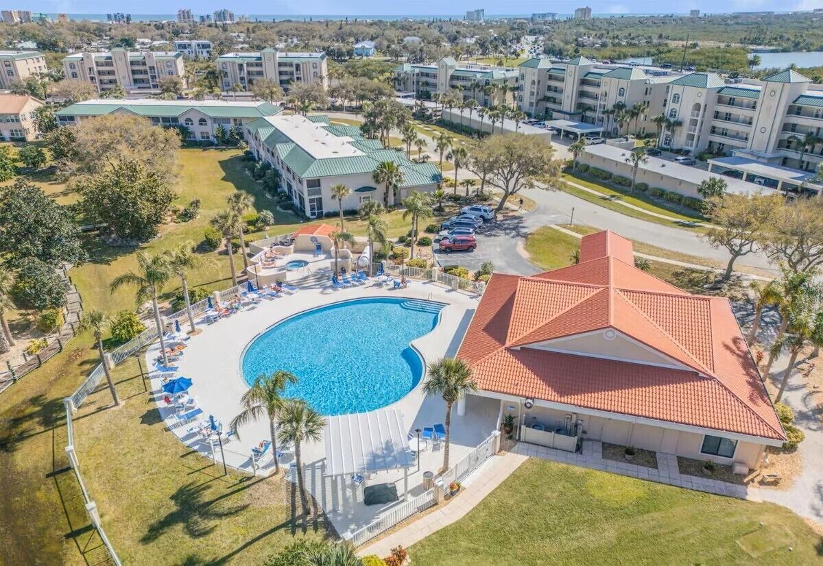 Un resort con una amplia piscina, varias construcciones y un estacionamiento.