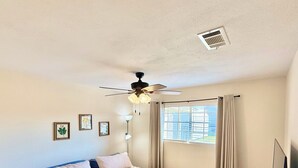 A bedroom with a bed, a ceiling fan, a window with curtains, a bedside table with a lamp, and a TV on a stand. - 3-bedroom, 2-bath home in Nederland with fence (nederland)