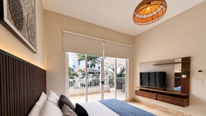 Ein Hotelzimmer mit einem Bett, einem Fernseher, einer Glastür zu einem Balkon und einer Deckenleuchte.