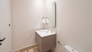Ein modernes Badezimmer mit einem weißen Waschbecken, Spiegel und WC.