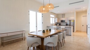 Eine moderne Küche mit Kochinsel, integrierten Geräten und einem Essbereich mit Holztisch und Stühlen.