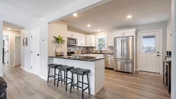 Una cocina moderna con una isla central, electrodomésticos de acero inoxidable y una zona de asientos con taburetes de bar.