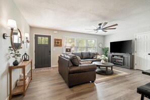 A living room with a sofa, a coffee table, a fireplace, and a television.