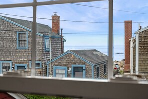 Un quartier résidentiel situé sur la côte, avec des maisons en bois, une vue dégagée sur la mer et un ciel clair.