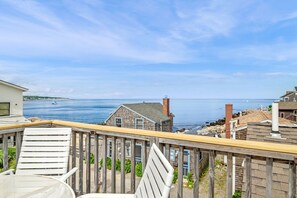 Une terrasse en bois offrant une vue sur la mer et les bâtiments.