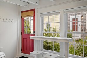 Ein Zimmer mit roter Tür, weißen Wänden und einem Fenster mit Blick auf Grün.