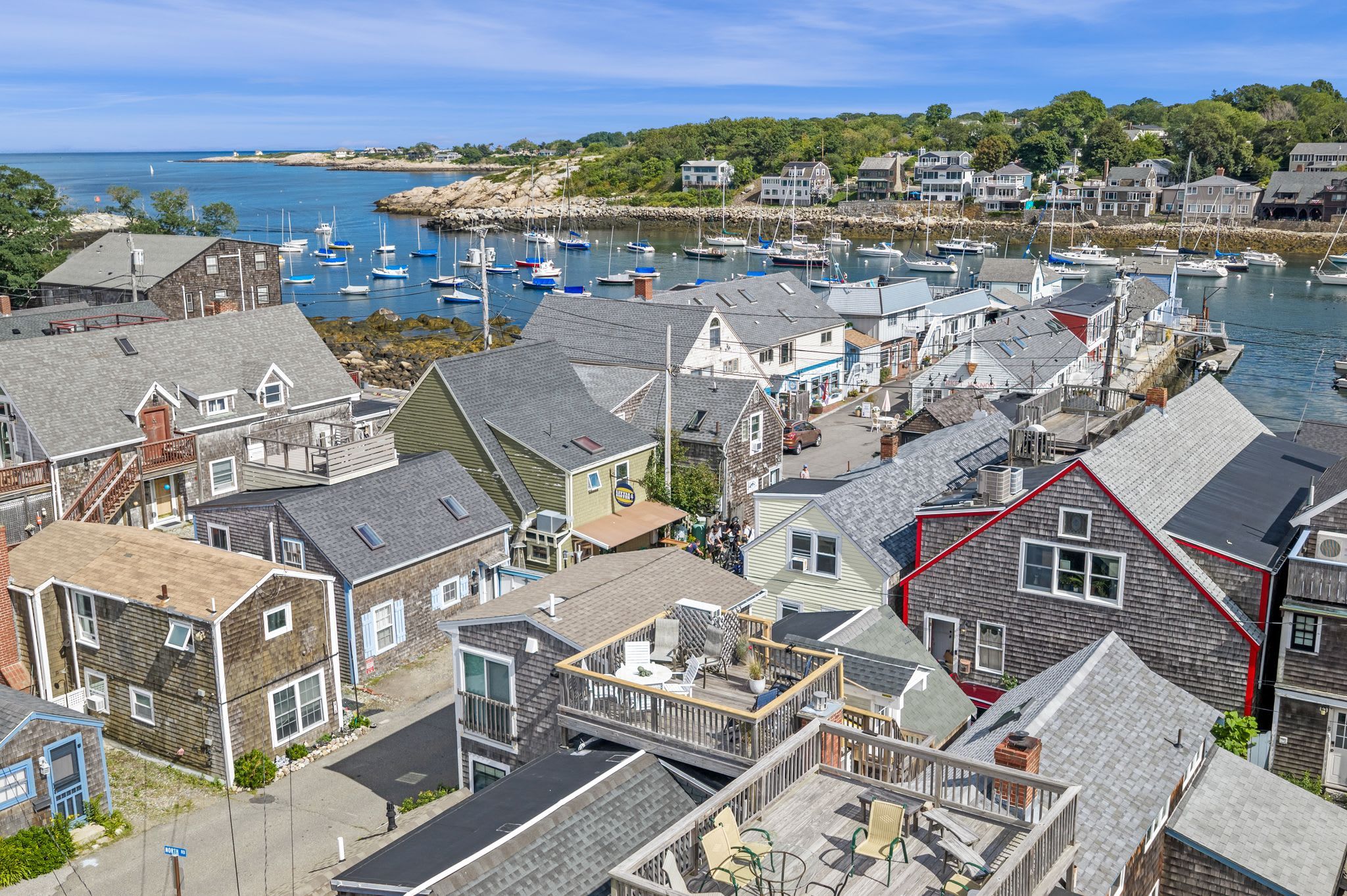 A coastal town with a marina, houses with various roof styles, and a clear view of the sea.