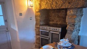 Uma sala de jantar com parede de pedra, forno embutido e mesa posta para dois.