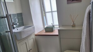 Casa de banho com chuveiro, sanita e lavatório.