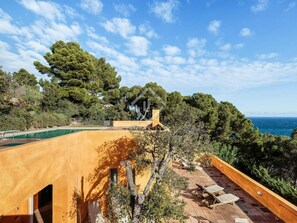 Ein Küsteneigentum mit Pool, Sitzgelegenheiten im Freien und Meerblick.
