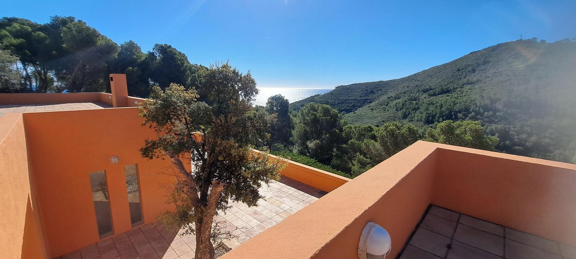 A terrace with a view of a mountainous landscape and a body of water.