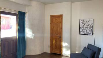 A room with a wooden door, a blue chair, and a framed artwork on the wall.