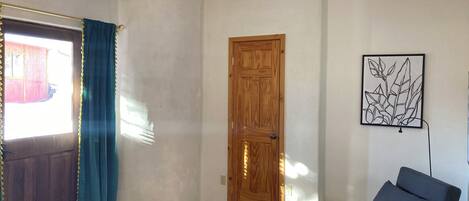 Una habitación con una puerta de madera, una silla azul y un cuadro en la pared.