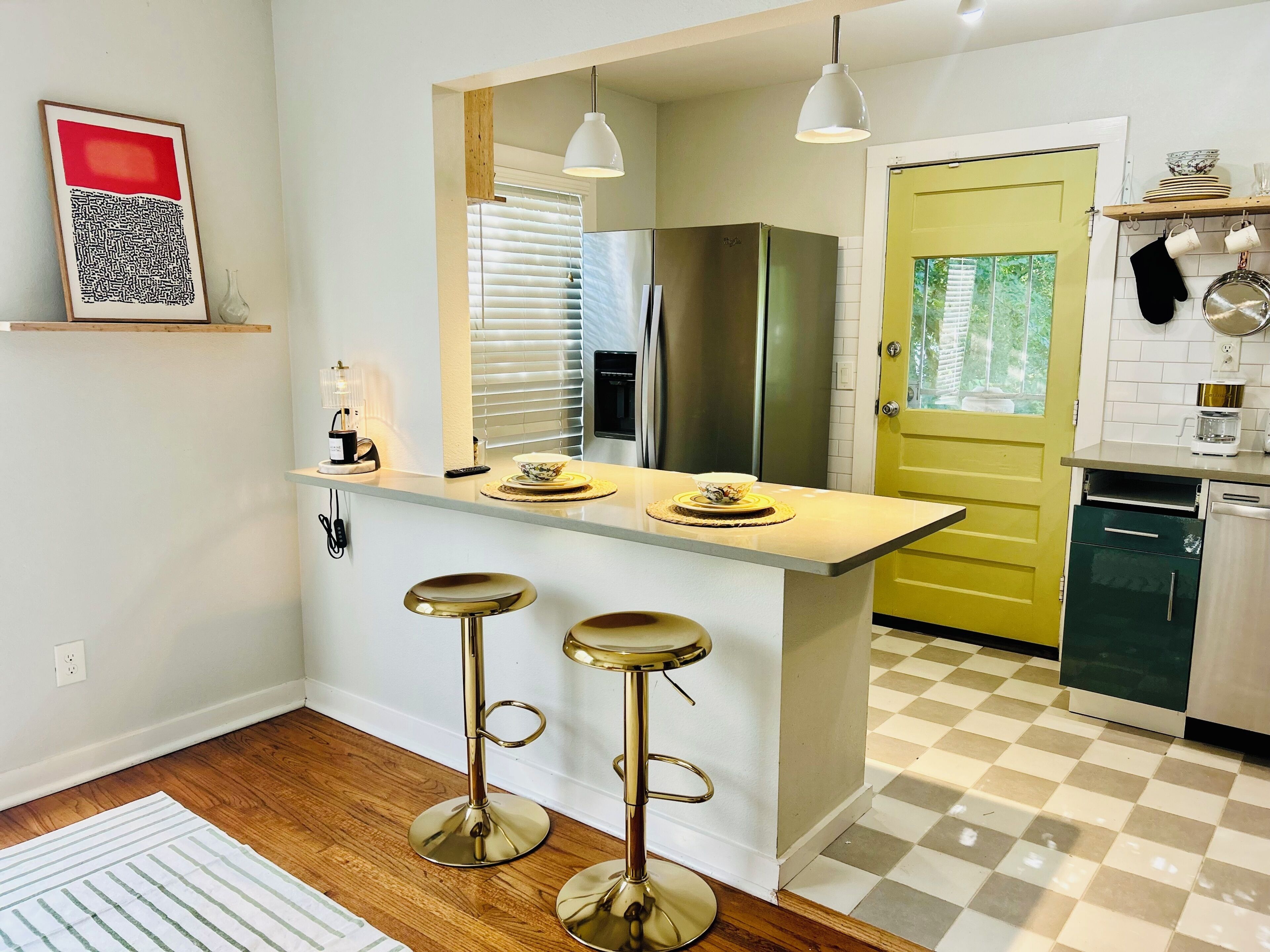 Una cocina con barra, un refrigerador y una puerta amarilla.